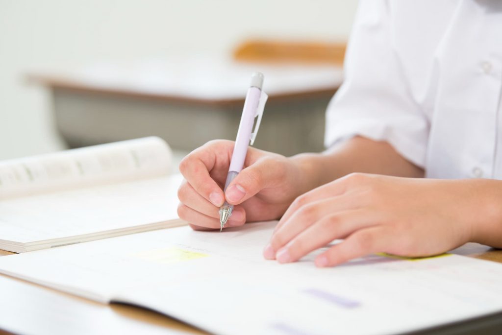 テキストを開きノートをとる授業中の学生の手元
